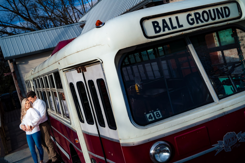 Couple snuggling by the ball ground burger bus engagement session in downtown ball ground georgia